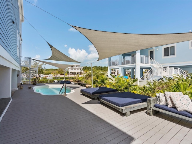 swimming pool featuring stairs, a jacuzzi, and a deck