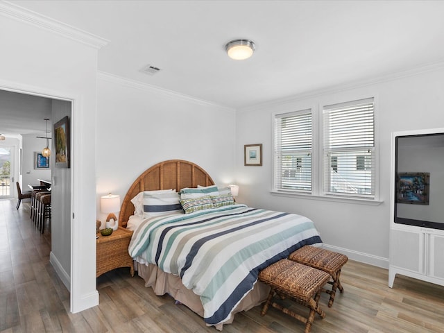 bedroom featuring crown molding, wood finished floors, and baseboards