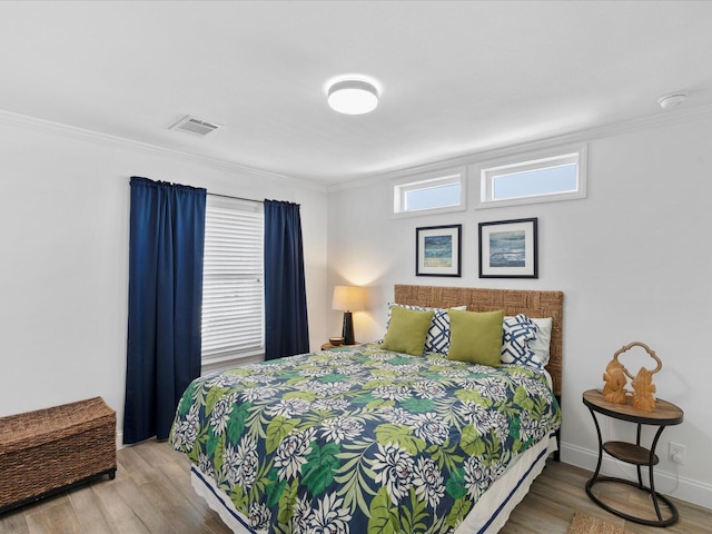 bedroom with wood finished floors and crown molding