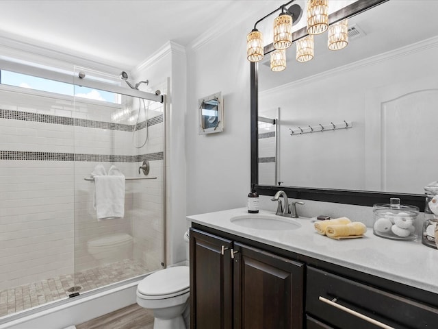 bathroom featuring a shower stall, crown molding, vanity, toilet, and wood finished floors