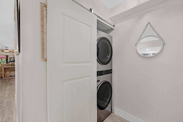 laundry area featuring stacked washer / dryer and light wood-type flooring