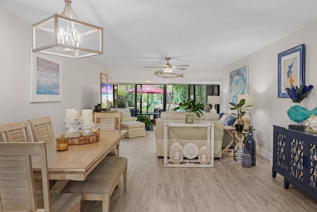 living room with ceiling fan with notable chandelier and light hardwood / wood-style floors