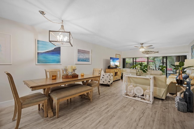 dining room with ceiling fan with notable chandelier and light hardwood / wood-style floors