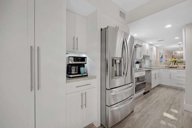 kitchen with sink, white cabinets, light stone counters, stainless steel appliances, and light wood-type flooring