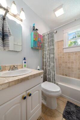 full bathroom with tile patterned flooring, vanity, toilet, and shower / bathtub combination with curtain