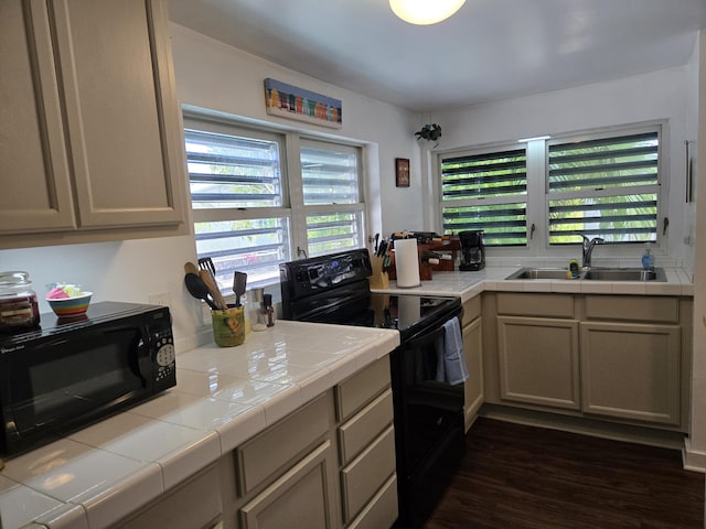 kitchen featuring a sink, black appliances, tile counters, and dark wood-style flooring