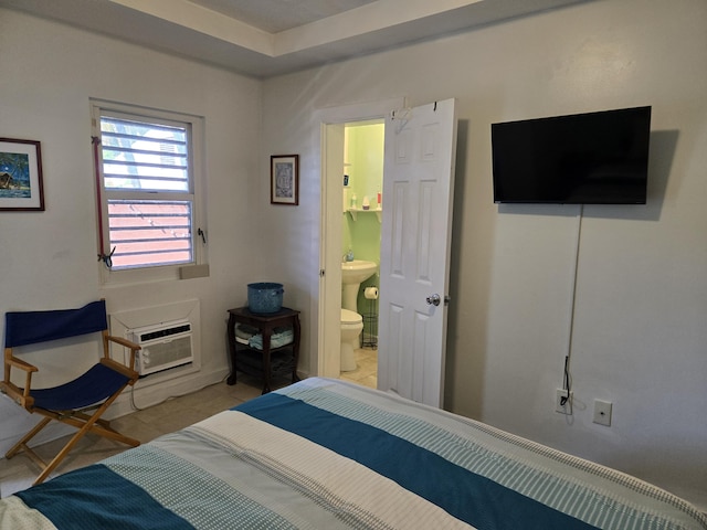 bedroom with a wall mounted air conditioner, connected bathroom, and light tile patterned floors