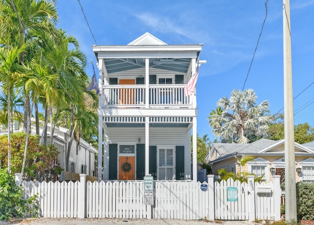 view of front facade featuring a balcony, covered porch, a fenced front yard, and a gate