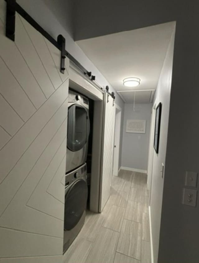 laundry room with stacked washer and dryer and a barn door