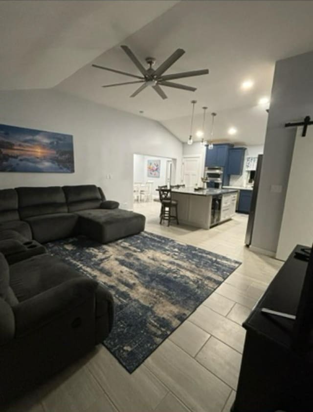 living room with vaulted ceiling, a barn door, and ceiling fan