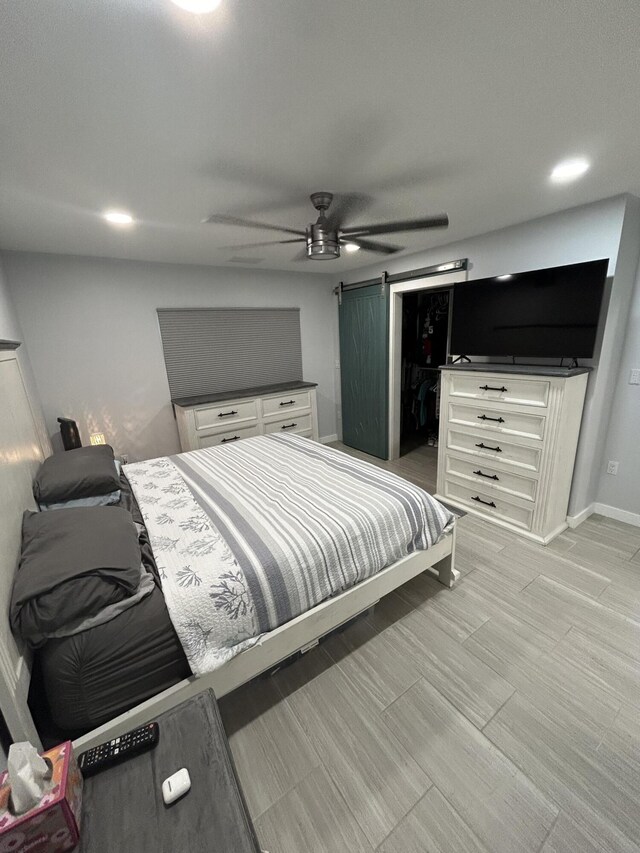 bedroom with ceiling fan and a barn door