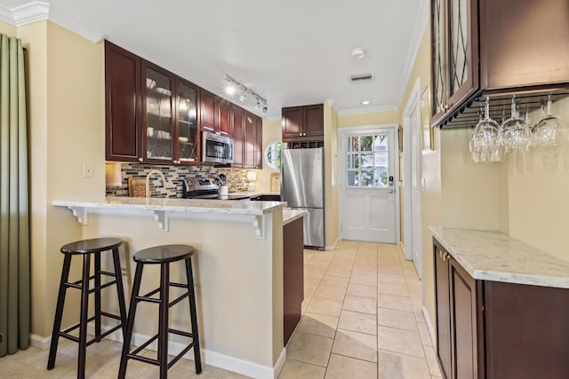 11 Kestral Way, Key West, FL 33040 - kitchen featuring appliances with stainless steel finishes, a breakfast bar area, backsplash, kitchen peninsula, and crown molding