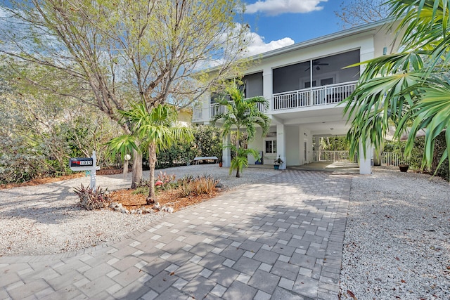 beach home with a sunroom, decorative driveway, stucco siding, and a carport