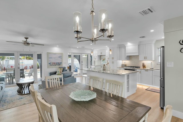 dining area with light wood-type flooring, visible vents, and a healthy amount of sunlight