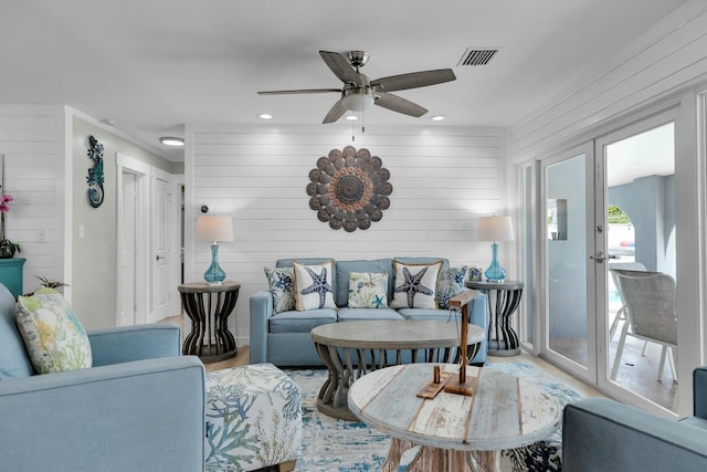 living area with recessed lighting, wooden walls, wood finished floors, visible vents, and a ceiling fan