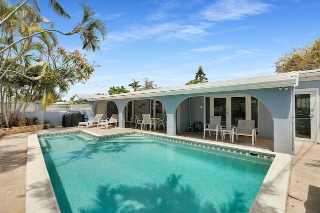 rear view of house featuring a fenced in pool, a patio, stucco siding, and fence