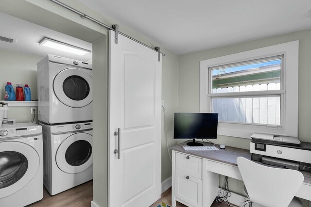 laundry room featuring a barn door, visible vents, light wood-style floors, stacked washing maching and dryer, and laundry area