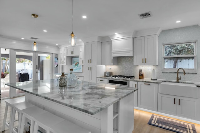 kitchen with white cabinets, visible vents, a healthy amount of sunlight, and a sink