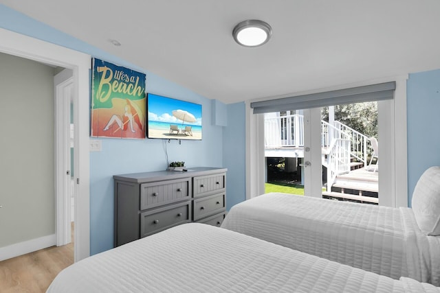 bedroom featuring baseboards, wood finished floors, and access to outside
