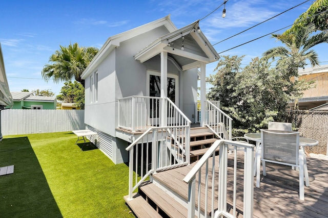 exterior space featuring fence, a yard, outdoor dining space, stucco siding, and a wooden deck