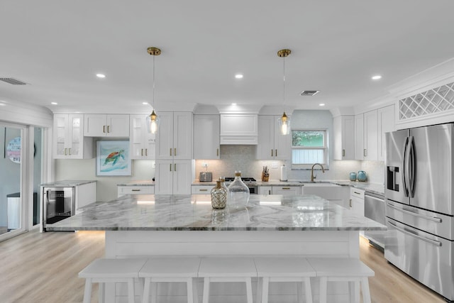 kitchen featuring stainless steel appliances, visible vents, light wood-style floors, and white cabinetry