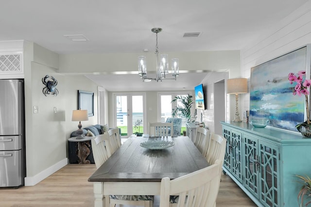 dining room with light wood-type flooring, visible vents, baseboards, and an inviting chandelier
