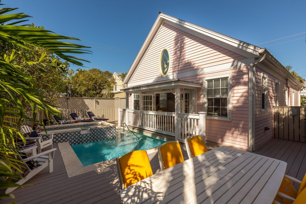 back of property with a fenced in pool, fence, and a wooden deck