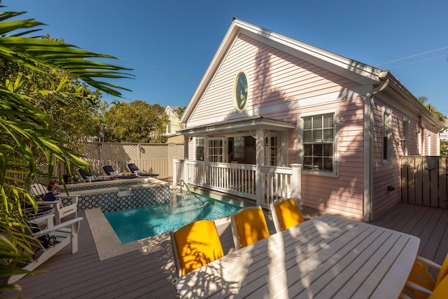 back of property with a fenced in pool, fence, and a wooden deck