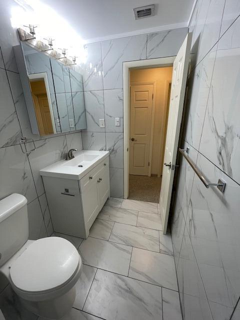 1608 Venetian Dr, Key West, FL 33040 - bathroom featuring tile walls, vanity, and marble look tiles