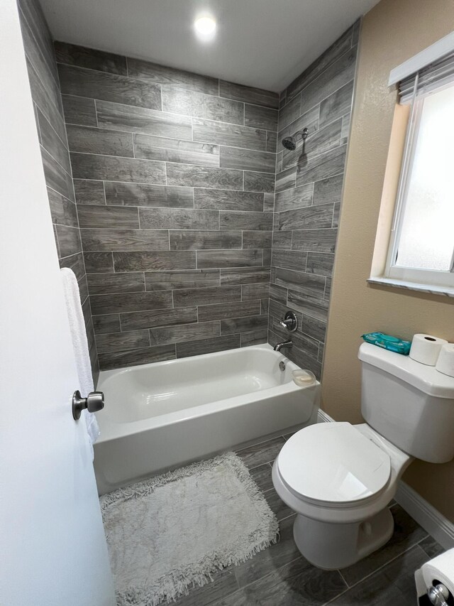 bathroom featuring wood-type flooring, toilet, and tiled shower / bath combo