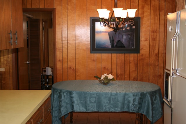 dining space featuring a chandelier and wooden walls