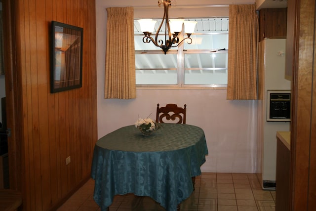 tiled dining area with a chandelier and wood walls