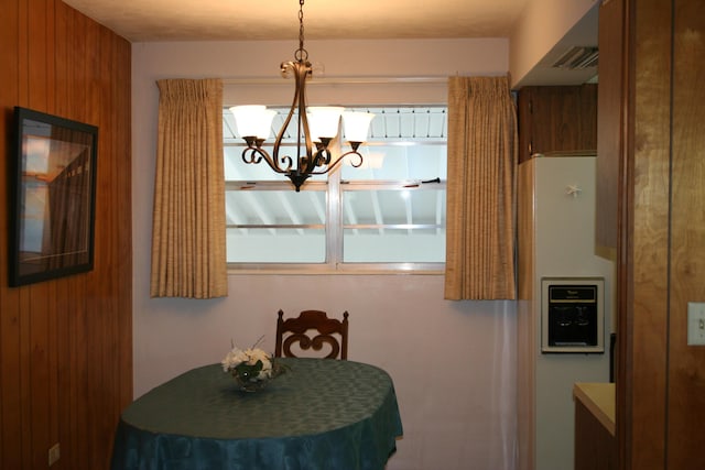 dining space featuring wooden walls and an inviting chandelier