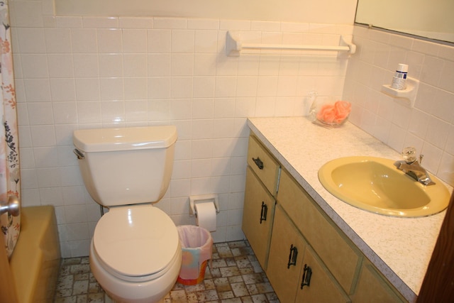 bathroom featuring vanity, toilet, and tile walls