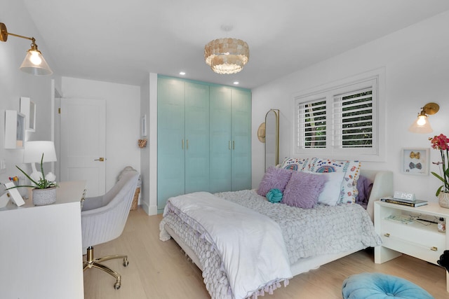 bedroom featuring an inviting chandelier, light wood-style flooring, a closet, and recessed lighting