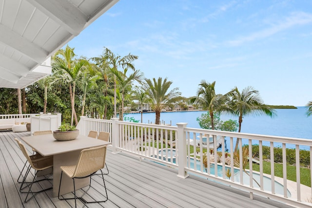 wooden deck with a water view, an outdoor pool, and outdoor dining space