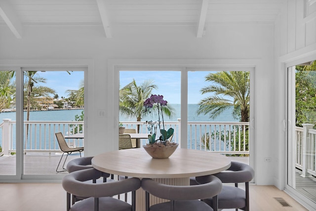 sunroom with beamed ceiling, a water view, and visible vents