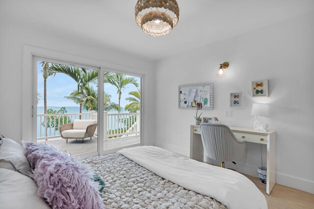 bedroom featuring a water view, access to exterior, and light hardwood / wood-style flooring