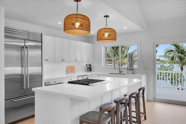 kitchen featuring a center island, light countertops, stainless steel built in fridge, a sink, and a kitchen bar