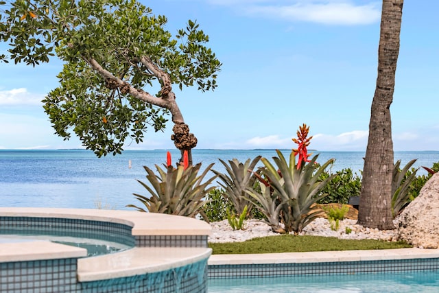 view of swimming pool with a water view and an in ground hot tub