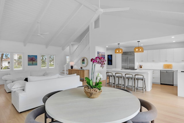 dining area featuring beamed ceiling, high vaulted ceiling, light wood-type flooring, and ceiling fan