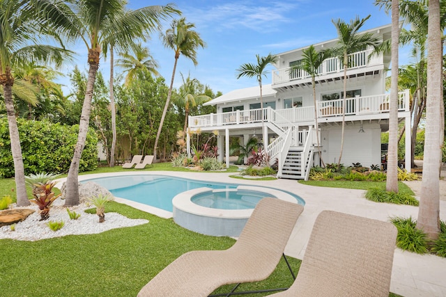 view of swimming pool featuring stairs, a yard, and a pool with connected hot tub