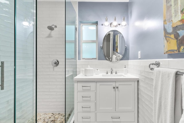 bathroom with tiled shower, vanity, and tile walls