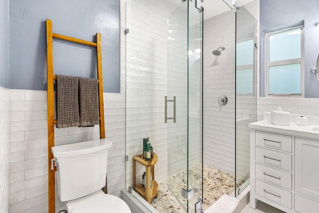 bathroom featuring walk in shower, vanity, toilet, and tile walls