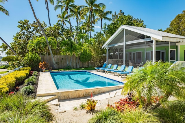 view of swimming pool with a patio area, a sunroom, and ceiling fan