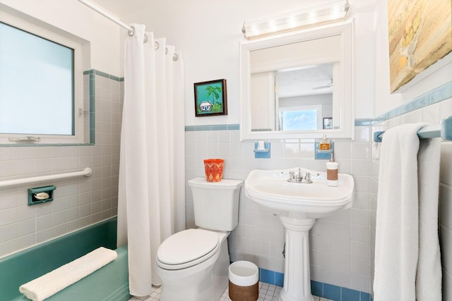 bathroom with tile patterned floors, toilet, shower / tub combo, and tile walls