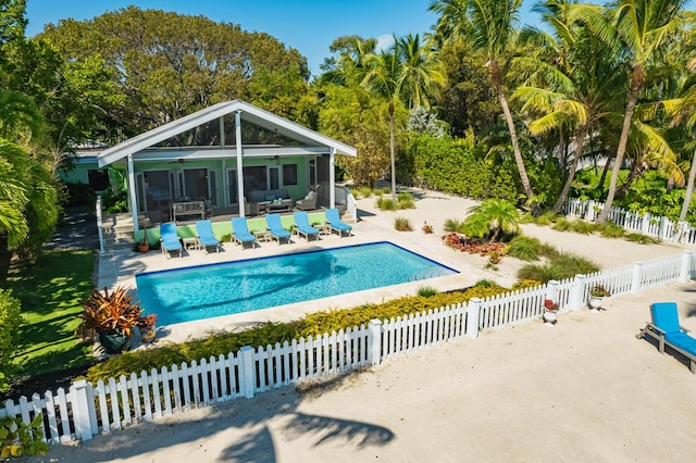 view of pool with a sunroom, ceiling fan, and a patio area