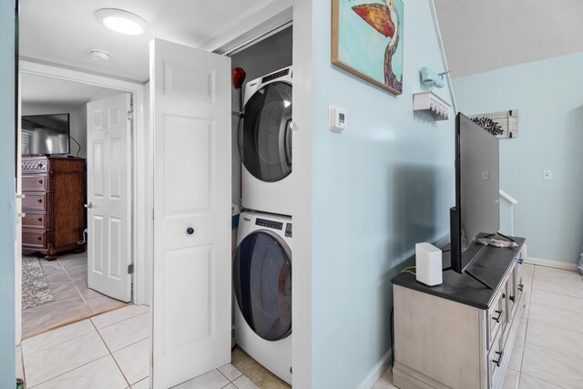 clothes washing area with light tile patterned floors and stacked washer and clothes dryer