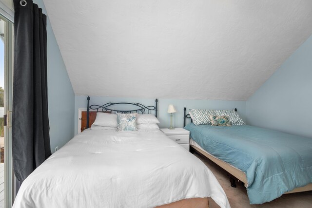 bedroom with multiple windows, vaulted ceiling, and a textured ceiling