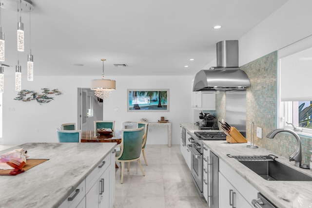 kitchen with island range hood, decorative light fixtures, tasteful backsplash, sink, and white cabinets